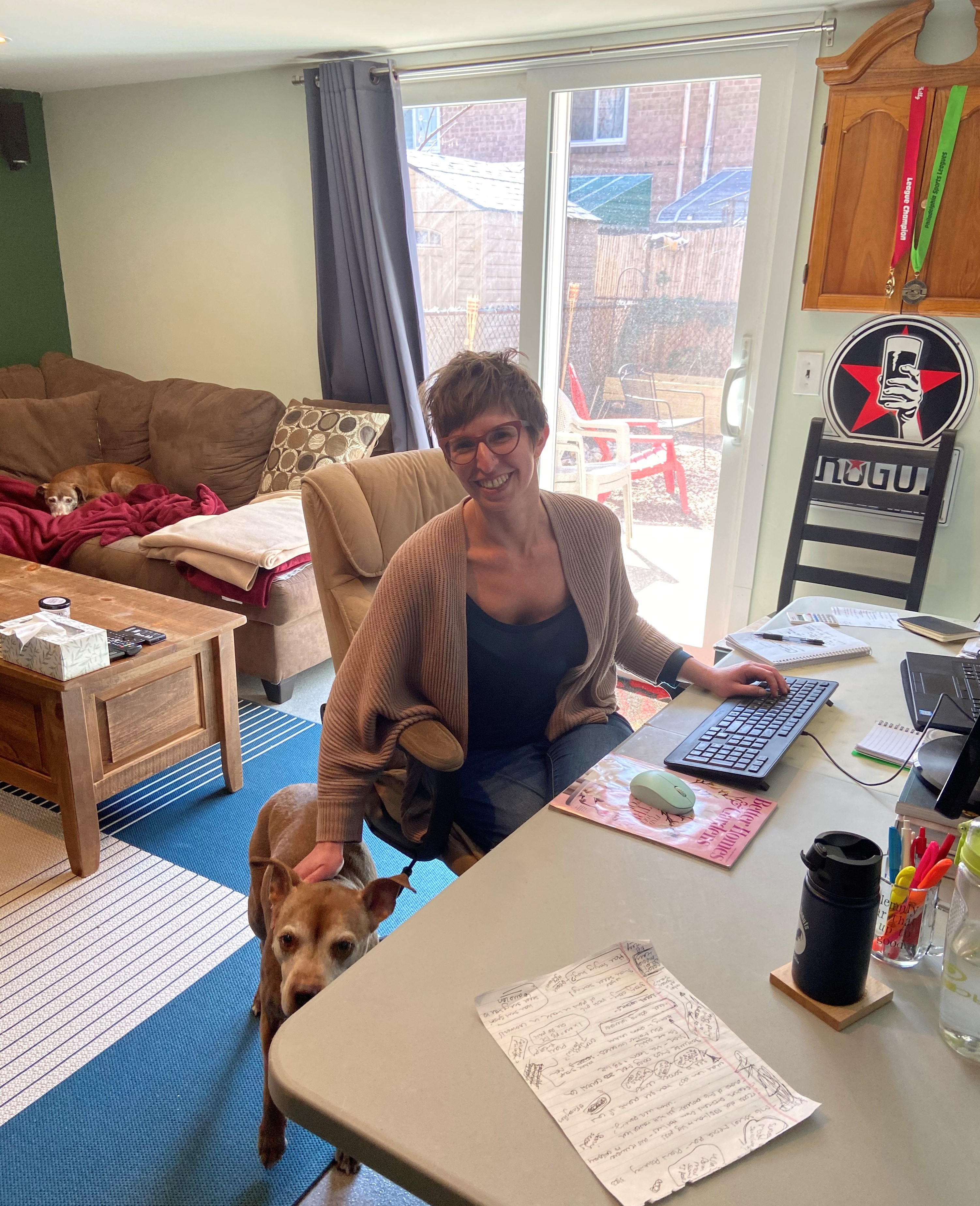 A woman with 2 dogs sitting at a desk